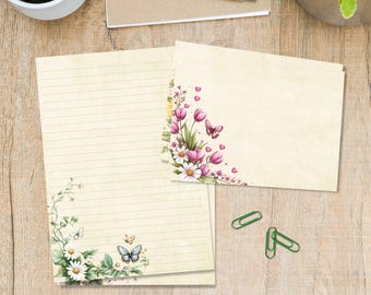 May include: Stationery set featuring lined and blank paper with floral and butterfly designs. The paper has a vintage, aged appearance. The floral arrangements include pink tulips, white daisies, and green foliage. Two green paper clips are also visible.