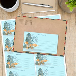 May include: A brown envelope with red, white, and blue edging, and a matching address label. The label and envelope feature a watercolour illustration of a fox and a decorated Christmas tree. Several address labels are visible.