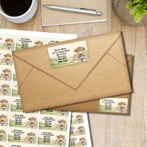 Peut inclure: Étiquettes d'adresse rectangulaires avec une illustration aquarelle d'une vache Highland derrière une clôture en bois. Le texte indique Sarah Black, 27 Longway Road, New Town, Barnsley, B77 8TT, England. Les étiquettes sont sur une feuille et une enveloppe.