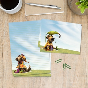 May include: Stationery set featuring a dog wearing a yellow floral raincoat and colourful boots. One sheet is lined with a dog illustration at the bottom, and the other is a blank card showing a dog under a large green leaf in the rain.