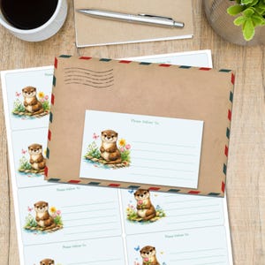 May include: A stationery set featuring a brown otter illustration with butterflies and flowers. The set includes an envelope with red, white, and blue trim, a matching address label, and sheets of address labels. The text "Please Deliver To:" is visible.