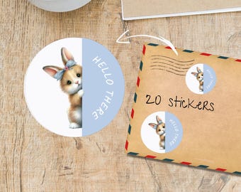 May include: Round sticker featuring a watercolor illustration of a bunny peeking out from behind a light blue section. The sticker has the text "HELLO THERE". An envelope with 20 stickers is also shown.