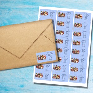 Peut inclure: Étiquettes d'adresse avec un fond bleu clair et une illustration de dessins animés d'oiseaux portant des écharpes et des chapeaux d'hiver. Une enveloppe marron est à côté de la feuille avec une étiquette d'adresse.