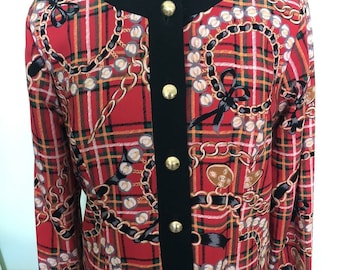 Op de afbeelding: Een rood en zwart geruit jasje met een ketting- en strikprint. Het jasje heeft een zwarte kraag en zwarte bies rond de voorste opening. Er zitten vier gouden knopen aan de voorkant van het jasje.