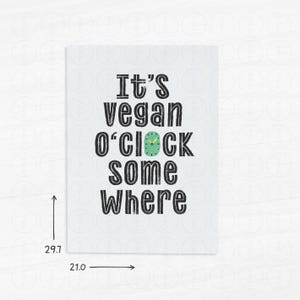 May include: A white card with black text that reads "It's vegan o'clock somewhere". A green clock face with yellow hands is in the middle of the text.