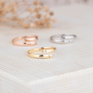 Puede incluir: Tres anillos de oro, plata y oro rosa con iniciales grabadas. El anillo de oro tiene las iniciales "R" y "L" grabadas.