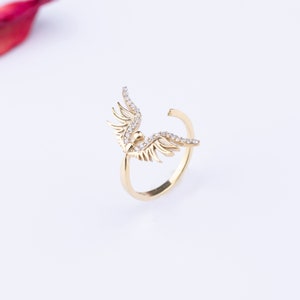 May include: A gold ring with a wing design set with clear sparkling stones.