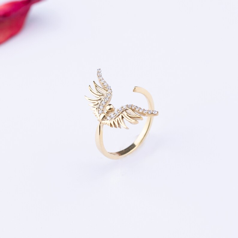 May include: A gold ring with a wing design set with clear sparkling stones.