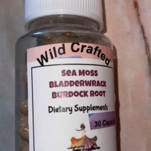 May include: A white bottle with a pink and white label that says "Wild Crafted Sea Moss Bladderwrack Burdock Root Dietary Supplements 30 Capsules". The bottle is filled with brown capsules.