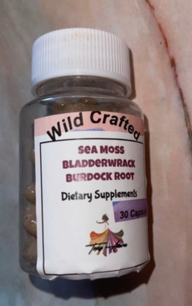 May include: A white bottle with a pink and white label that says "Wild Crafted Sea Moss Bladderwrack Burdock Root Dietary Supplements 30 Capsules". The bottle is filled with brown capsules.