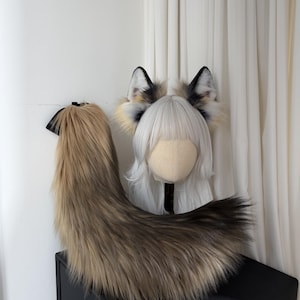 May include: A faux fur fox tail and ears set. The tail is a blend of brown and tan, with a black accent. The ears are white, tan, and black. The set is designed for cosplay or costume use.
