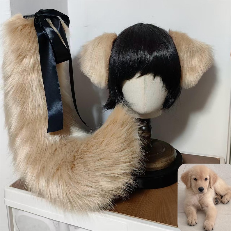 May include: A set of faux fur accessories including a long, light tan tail with a black satin ribbon bow and a black wig featuring attached light tan animal ears. The set is displayed on a mannequin head next to a photo of a golden retriever puppy.