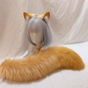 Op de afbeelding: Een cosplay set met een haarband met vossenoren en een bijpassende staart. De oren zijn bruin met witte details aan de binnenkant, en de staart is lang, pluizig en oranje-bruin. Perfect voor kostuums of thema-evenementen.