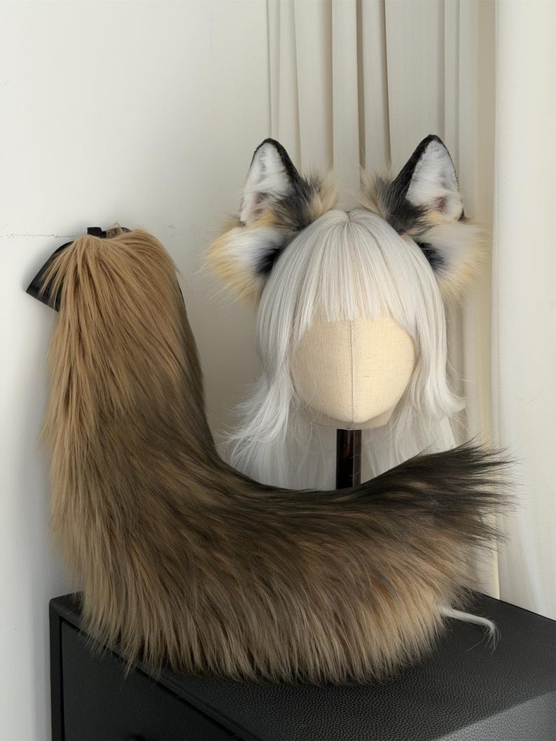 May include: A faux fur fox tail and headband with ears. The tail is brown and black, and the ears are white, black, and tan. The headband has a white wig attached to it.