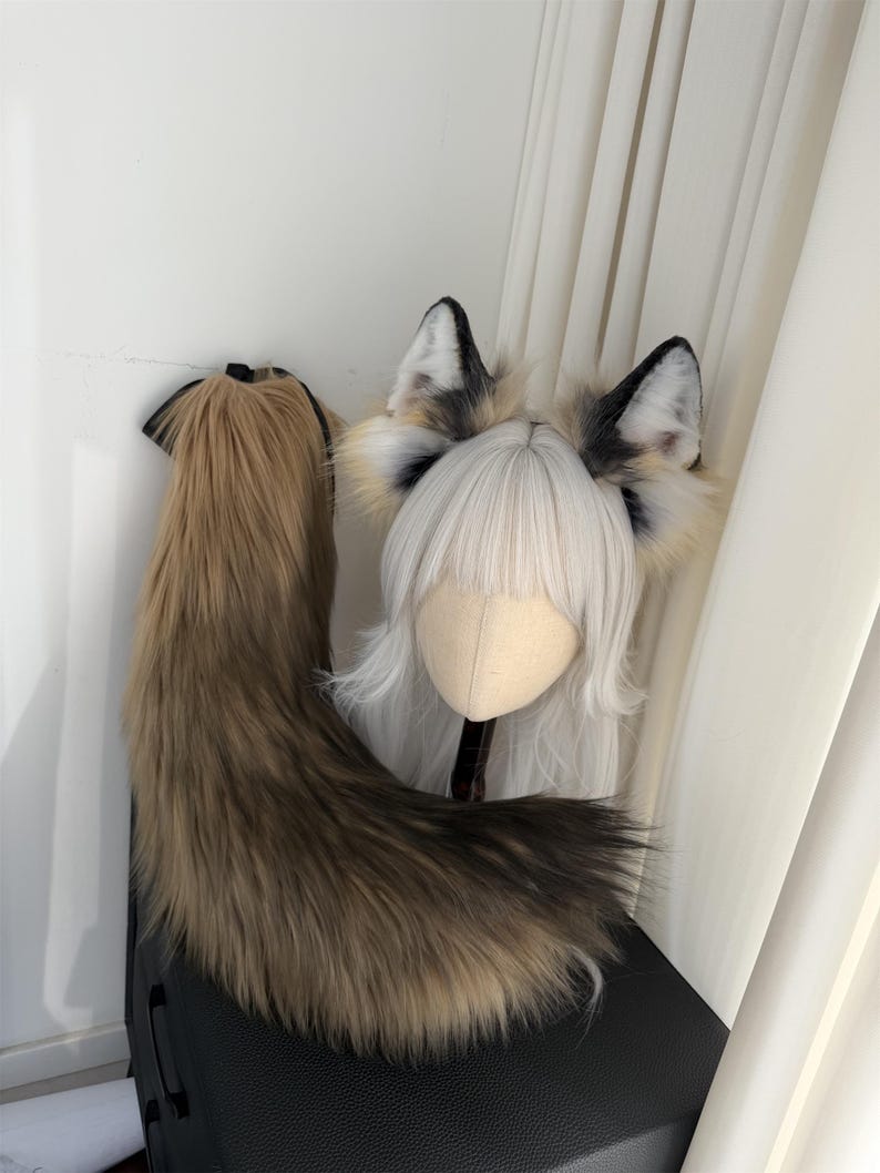 May include: A cosplay set featuring a faux fur tail and ears. The tail is a blend of brown and tan, while the ears have black tips and a white interior. A wig with white hair is also included.