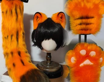 Könnte beinhalten: Ein Cosplay-Set mit einem langen, orange-schwarz gestreiften Schwanz mit schwarzer Schleife, einer Perücke mit orange-schwarzen Katzenohren und zwei orangefarbenen, pfotenförmigen Handabdeckungen. Das Set ist als Tiger gestaltet.
