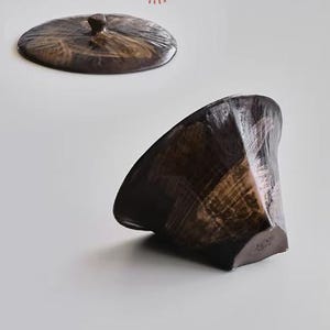 Pu&ograve; includere: Una ciotola in ceramica marrone scuro con un design geometrico testurizzato. La ciotola ha un'apertura larga e svasata e una base stretta. La ciotola &egrave; realizzata in argilla marrone scuro e ha una finitura lucida.