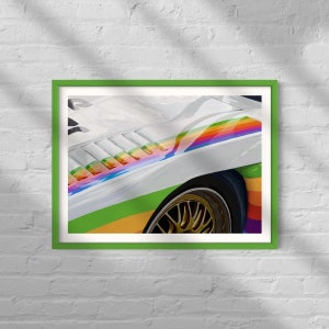 Può includere: Un'auto da corsa bianca con una striscia arcobaleno e ruote dorate. L'auto ha una striscia verde, gialla, arancione, rossa, blu e viola.