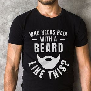 May include: Black t-shirt with white text that reads "Who needs hair with a beard like this?" and a white cartoon beard.