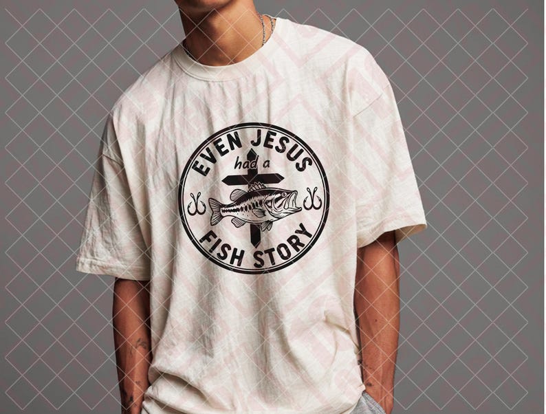 May include: Cream-colored t-shirt featuring a circular graphic with the text "EVEN JESUS had a FISH STORY." The graphic includes a fish, cross, and fishing hooks. The shirt is a casual, short-sleeved design.