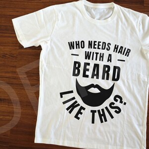May include: White t-shirt with black text that reads "Who needs hair with a beard like this?" and a black silhouette of a beard.