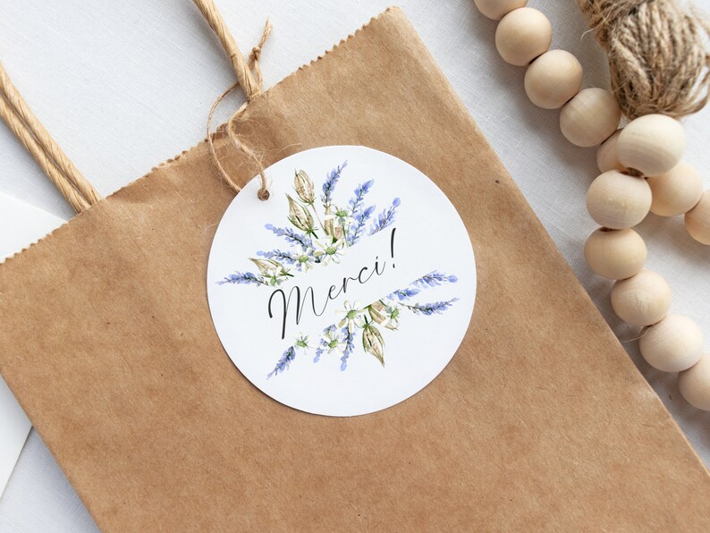 May include: A white round gift tag with a watercolor illustration of lavender flowers and the word "Merci!" in black calligraphy.