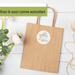 May include: A brown paper gift bag with a round sticker that says "Merci!" in black script. The sticker has a watercolor design of blue flowers and green leaves.