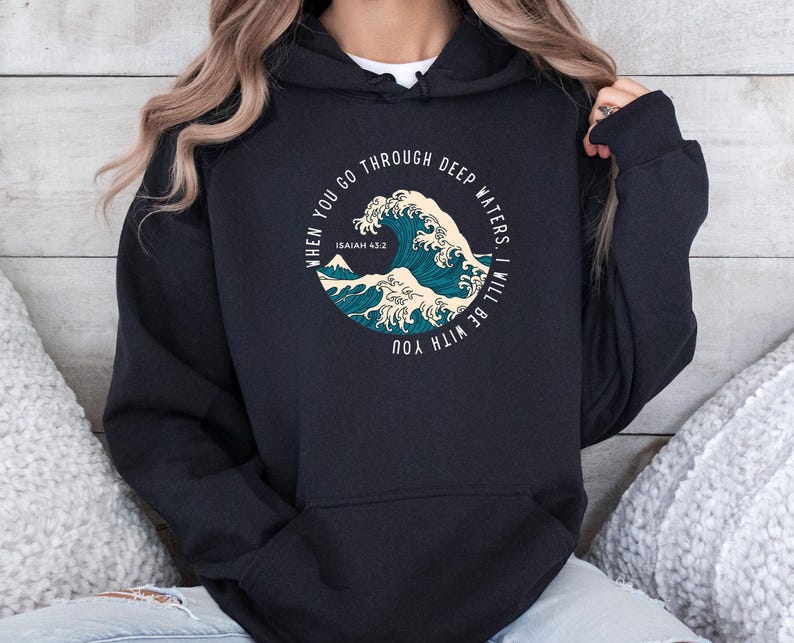 K&ouml;nnte beinhalten: Schwarzer Hoodie mit einem Grafikdruck einer Welle und dem Text "When you go through deep waters, I will be with you. Isaiah 43:2"
