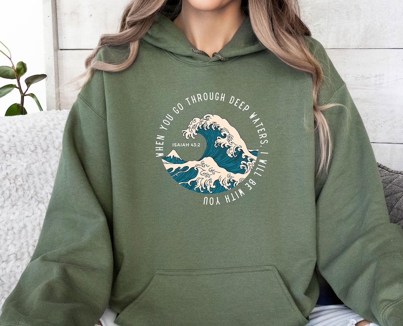 K&ouml;nnte beinhalten: Ein gr&uuml;ner Kapuzenpullover mit einem grafischen Aufdruck einer Welle und dem Text "WHEN YOU GO THROUGH DEEP WATERS, I WILL BE WITH YOU" und "ISAIAH 43.2".