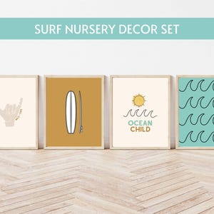 May include: A set of four framed art prints with a surf nursery theme. The prints feature a hand gesture, a surfboard, a sun with waves and the text "Ocean Child", and a pattern of waves. The frames are light brown.