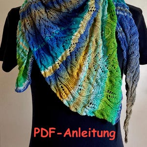 Könnte beinhalten: Ein farbenfroher, gestrickter Schal in Blau-, Grün- und Gelbtönen. Der Schal hat ein detailliertes Lochmuster und ist über einem schwarzen Hintergrund drapiert. Der Text "PDF-Anleitung" ist im Bild sichtbar.