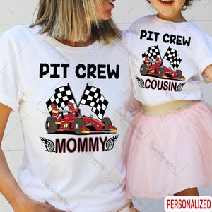 Pu&ograve; includere: Due magliette bianche con una grafica di un'auto da corsa rossa e bandiere a scacchi. Il testo sulle magliette recita "Pit Crew Mommy" e "Pit Crew Cousin".