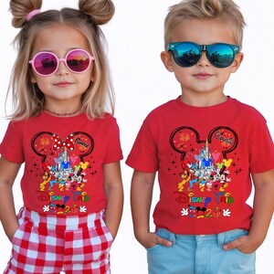 K&ouml;nnte beinhalten: Zwei Kinder tragen rote T-Shirts mit einem Disney-Motiv. Die Shirts zeigen einen Mickey-Mouse-Kopfumriss, ein Schloss und verschiedene Disney-Figuren. Auf einem Shirt steht "Name" und auf dem anderen "Cousin". Auf den Shirts steht auch "Disney Trip 2020".
