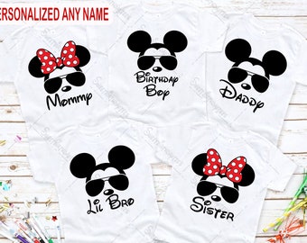 Op de afbeelding: Vijf witte T-shirts met verschillende ontwerpen met een cartoon van Mickey Mouse en Minnie Mouse. De shirts hebben de tekst "Mommy", "Birthday Boy", "Daddy", "Lil Bro" en "Sister" erop gedrukt.