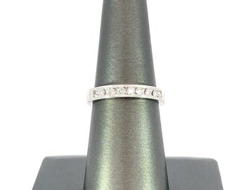 May include: A silver band ring with a row of small, clear diamonds set in a channel setting.