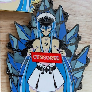 May include: A blue and silver enamel pin featuring an anime character with long blue hair, a white dress, and a black jacket. The character is holding a red sign that says "CENSORED".