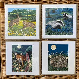 Può includere: Quattro stampe artistiche quadrate con scene di fauna selvatica. Una stampa mostra due lepri in un campo, un'altra raffigura tassi in una foresta, una volpe e un riccio sotto la luna piena.