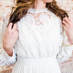 May include: A white lace dress with long sleeves and a high neckline.