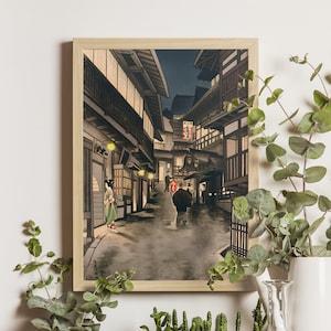 May include: A vintage Japanese woodblock print depicting a nighttime street scene in a traditional Japanese town. The street is lined with buildings and lanterns, and there are people walking along the street. The print is in shades of grey, brown, and black.