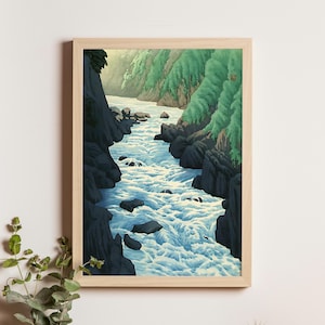 Puede incluir: Una impresión enmarcada de un río que fluye a través de un cañón rocoso. La obra de arte presenta una paleta de colores vibrantes con tonos de azul, verde y negro. El agua del río se representa como rápidos blancos, contrastando con las rocas oscuras y el follaje verde.
