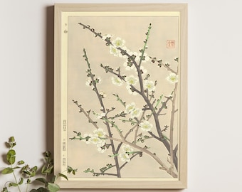 May include: A framed print of a Japanese woodblock print depicting a branch of a flowering plum tree with white blossoms. The print is on a cream-colored background and has a light brown frame.