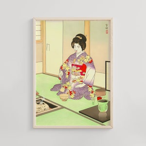 May include: A woman in a purple and red kimono with floral patterns sits on a green mat, preparing a tea ceremony. She holds a whisk in her right hand and a teacup in her left. There are two other teacups and a teapot on the mat. The background is a light green wall with a wooden door.