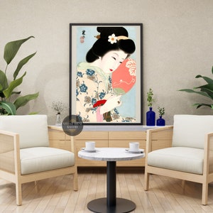 K&ouml;nnte beinhalten: Ein japanischer Holzschnitt aus der Zeit, der eine Frau in einem Blumen-Kimono zeigt, die einen roten F&auml;cher h&auml;lt. Die Frau hat schwarzes Haar und tr&auml;gt eine wei&szlig;e Blume im Haar. Der Hintergrund ist hellblau.