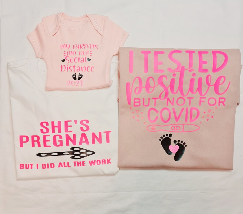 May include: A set of three pink and white shirts with a pregnancy announcement theme. The baby onesie says "My parents did not social distance 2021". The larger shirt says "She's pregnant but I did all the work". The third shirt says "I tested positive but not for COVID" with a pregnancy test and footprints.