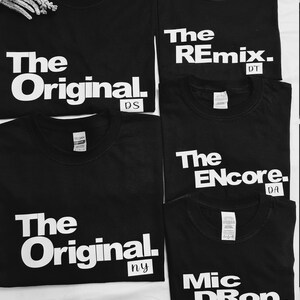 May include: Five black t-shirts with white text. The shirts read "The Original", "The Remix", "The Encore", "The Original", and "Mic Drop".