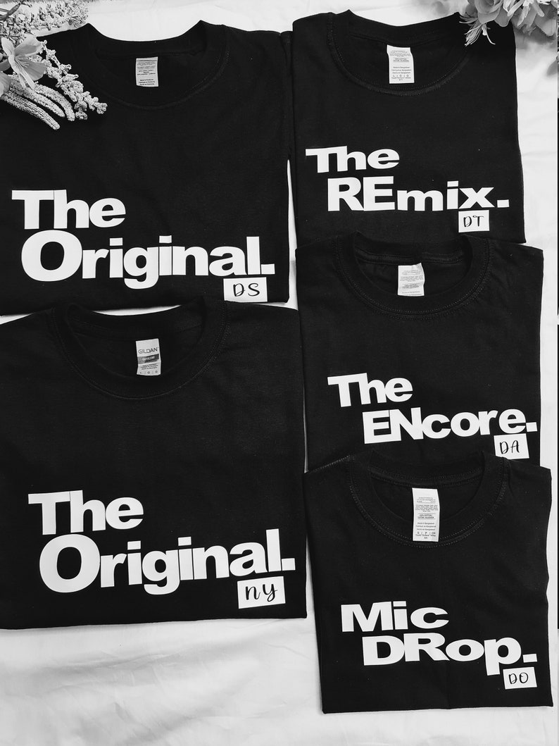 May include: Five black t-shirts with white text. The shirts read "The Original", "The Remix", "The Encore", "The Original", and "Mic Drop".