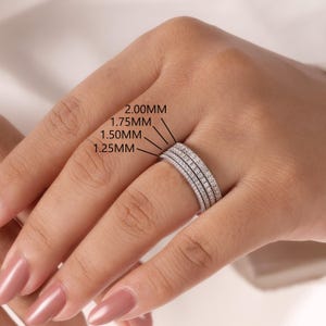 Puede incluir: Cuatro anillos de eternidad en tono plateado con pequeñas piedras incrustadas. Los anillos están etiquetados con anchos de 1.25 mm, 1.50 mm, 1.75 mm y 2.00 mm, lo que indica el grosor variable de cada banda al estar apiladas en un dedo.