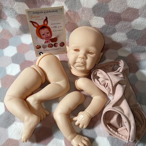 Puede incluir: Un conjunto de piezas de mu&ntilde;eca reborn sin pintar, que incluye una cabeza, brazos y piernas. Las piezas de la mu&ntilde;eca son de vinilo y est&aacute;n listas para ser pintadas y ensambladas. Las piezas de la mu&ntilde;eca est&aacute;n dispuestas sobre una manta rosa y gris. Las piezas de la mu&ntilde;eca est&aacute;n a la venta en Etsy.