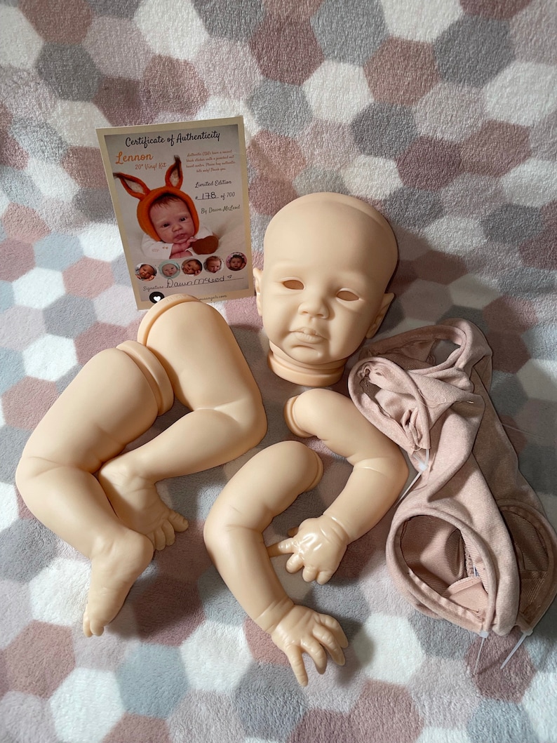 Puede incluir: Un conjunto de piezas de mu&ntilde;eca reborn sin pintar, que incluye una cabeza, brazos y piernas. Las piezas de la mu&ntilde;eca son de vinilo y est&aacute;n listas para ser pintadas y ensambladas. Las piezas de la mu&ntilde;eca est&aacute;n dispuestas sobre una manta rosa y gris. Las piezas de la mu&ntilde;eca est&aacute;n a la venta en Etsy.