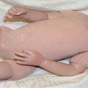 Może przedstawiać: Niemalowany zestaw dla lalek dla niemowląt, z winylową głową, ramionami i nogami. Zestaw ten jest przeznaczony do tworzenia realistycznej lalki reborn. Skóra lalki ma miękki, brzoskwiniowy odcień, a kończyny są szczegółowe.